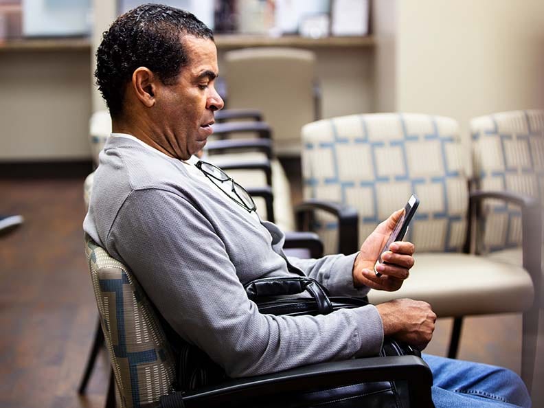 Man looking at cell phone in doctor's waiting room