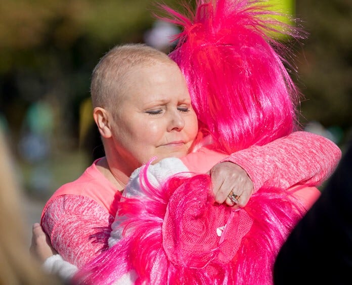 Two people hugging wearing pink at a Making Strides Against Breast Cancer event
