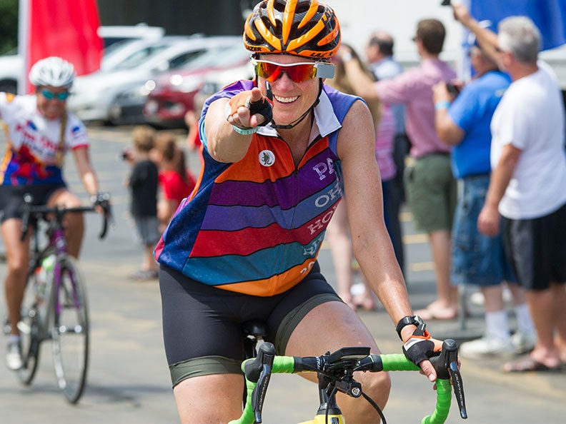 Smiling Determination participant riding bike with crowd in background