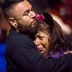 A man consoles a crying woman in his arms.