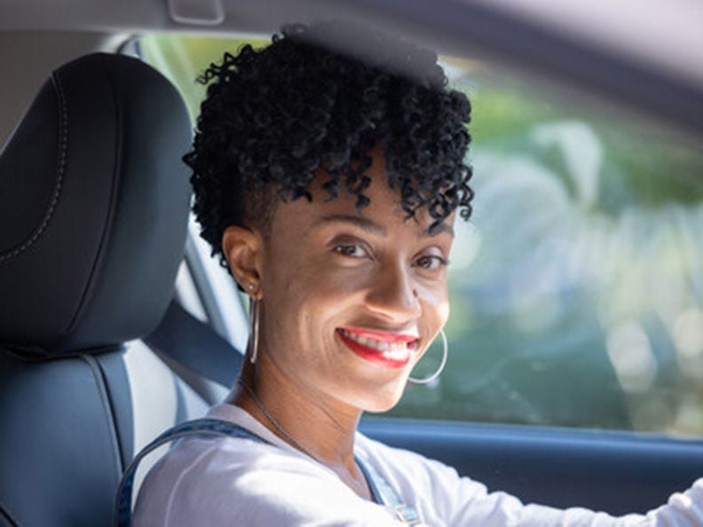 black woman sitting in a car's drivers seat looking at camera